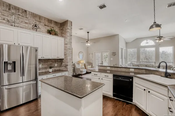 a kitchen with a sink a stove a refrigerator and white cabinets