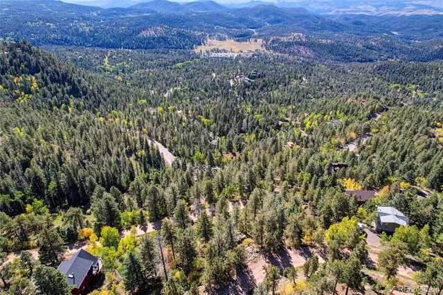 an aerial view of residential house with outdoor space and trees all around