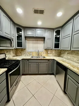 a kitchen with stainless steel appliances granite countertop a refrigerator and a stove top oven