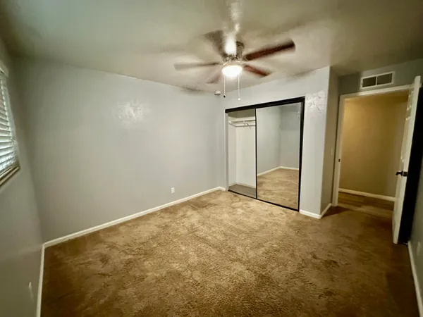 an empty room with closet and a ceiling fan