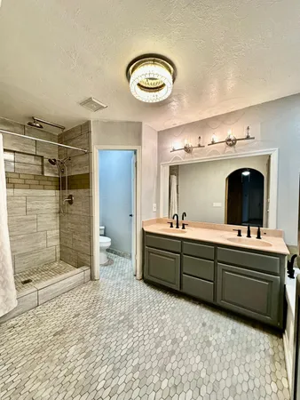 a spacious bathroom with a granite countertop sink mirror and bathtub