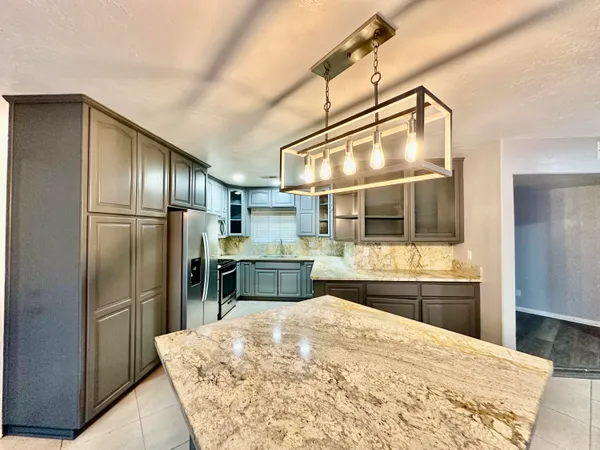a kitchen with stainless steel appliances kitchen island granite countertop a refrigerator and stove