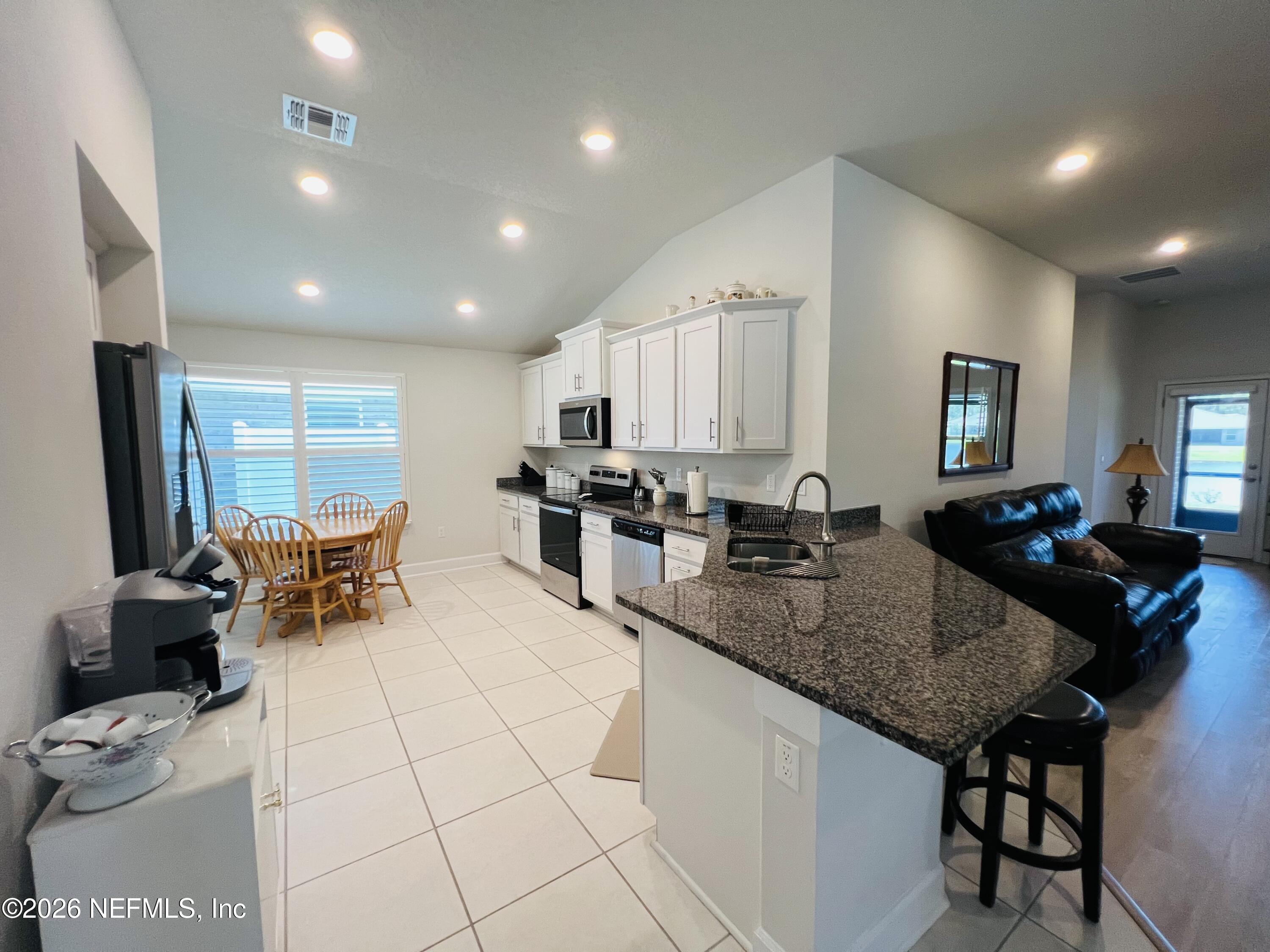 2 Rivertown Road Palm Coast, FL 32137 - Photo 33 of 80 a kitchen with granite countertop a stove a sink a dining table and chairs