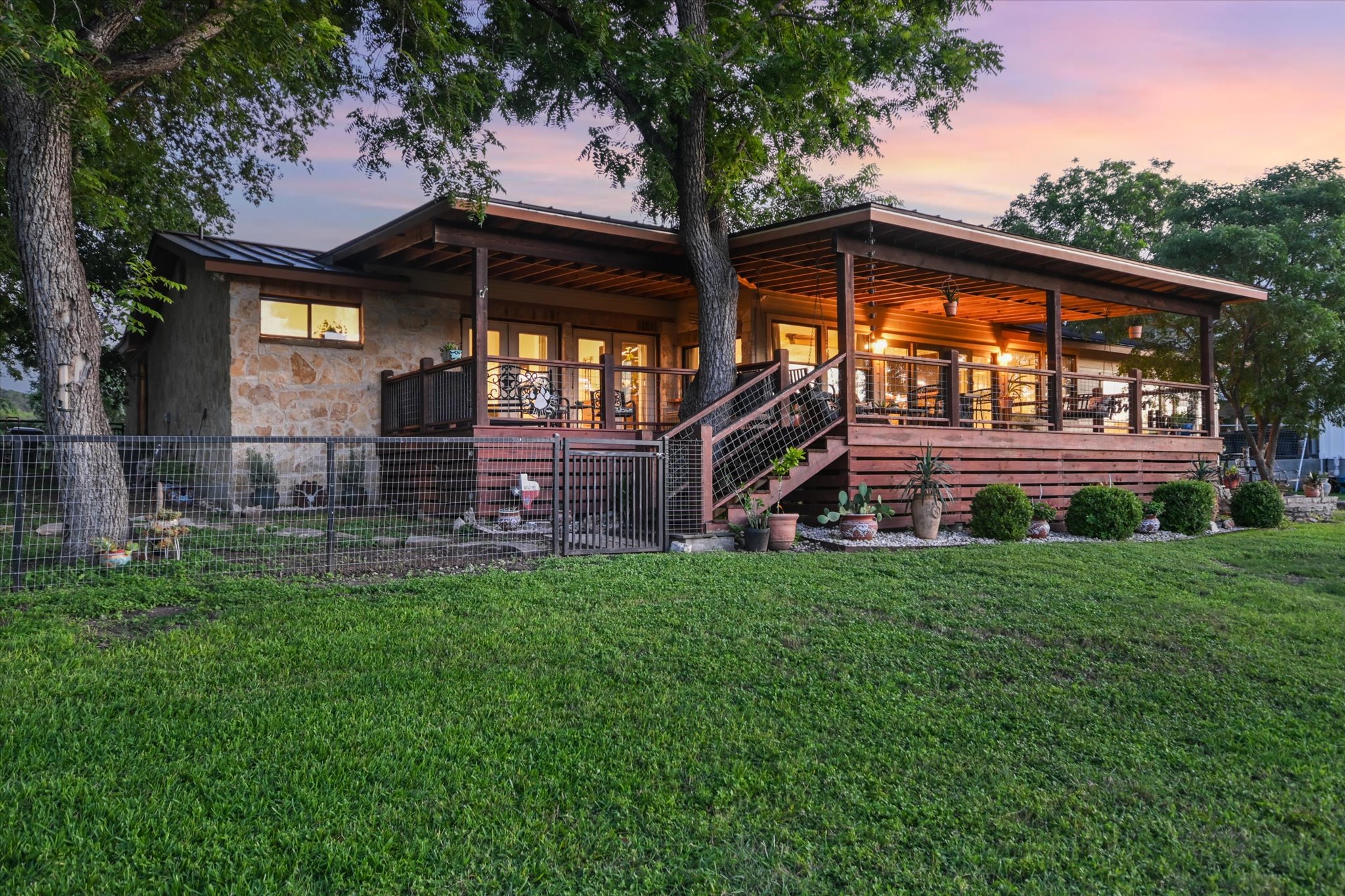 2411 Spoke Hollow Road Wimberley, TX 78676 - Photo 24 of 37 A spacious elevated wooden deck and stone siding create an inviting outdoor living space with abundant natural light.