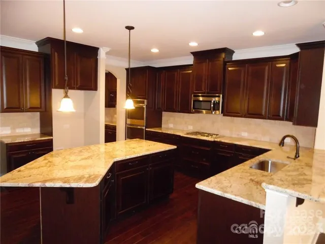 a kitchen with stainless steel appliances kitchen island granite countertop a sink refrigerator and cabinets