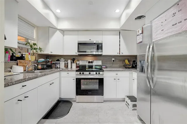 a kitchen with granite countertop white cabinets and white appliances