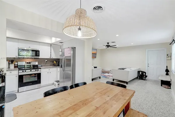 a kitchen with kitchen island stainless steel appliances a stove refrigerator dining table and chairs