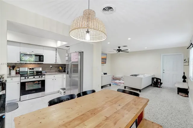 a kitchen with kitchen island stainless steel appliances a stove refrigerator dining table and chairs