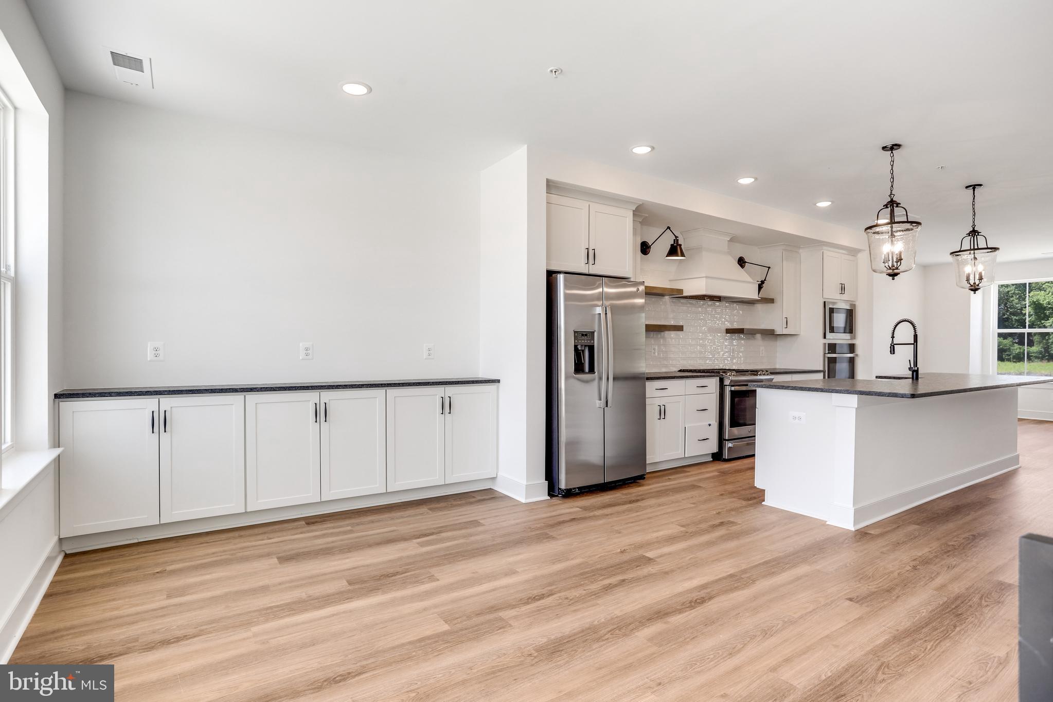 751 Elevation Road Frederick, MD 21702 - Photo 14 of 35 a kitchen with stainless steel appliances kitchen island wooden floors and white cabinets