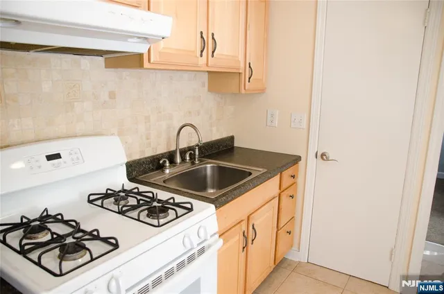 a kitchen with sink a stove and white cabinets