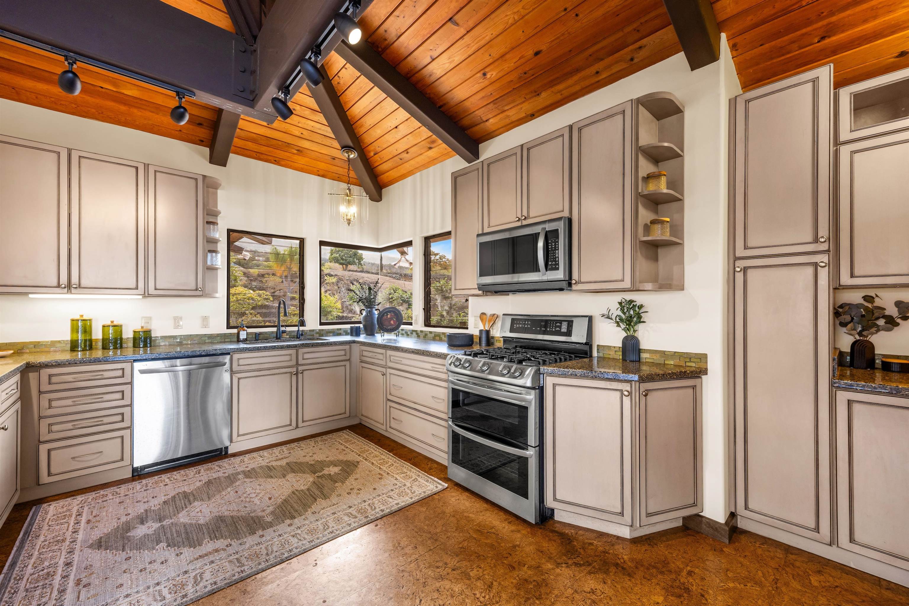 110 Kamehameiki Road Kula, HI 96790 - Photo 13 of 50 a kitchen with stainless steel appliances granite countertop a stove top oven a sink dishwasher a refrigerator and white cabinets with wooden floor