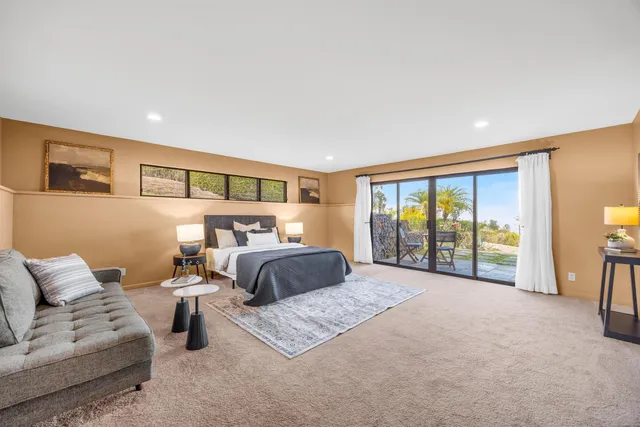 a spacious bedroom with a bed a couch and a large window