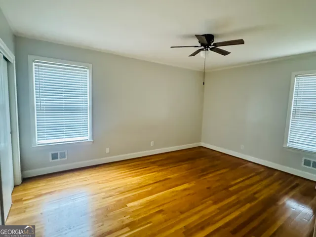 a view of empty room with wooden floor and fan