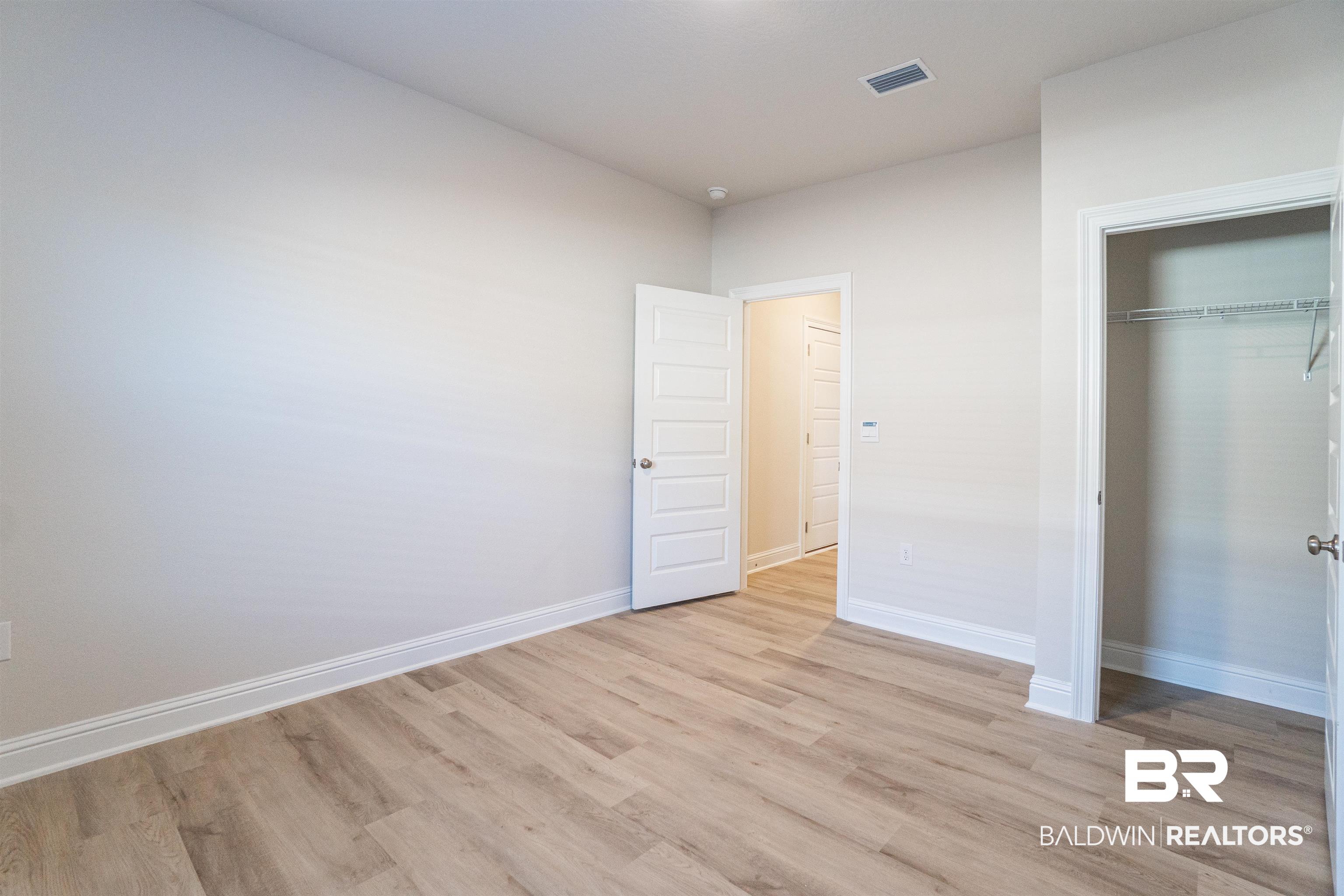 1073 Hayward Loop Foley, AL 36535 - Photo 8 of 18 Spacious room featuring light wood-finish flooring, neutral wall tones, white trim, a solid core door, and a closet with wire shelving