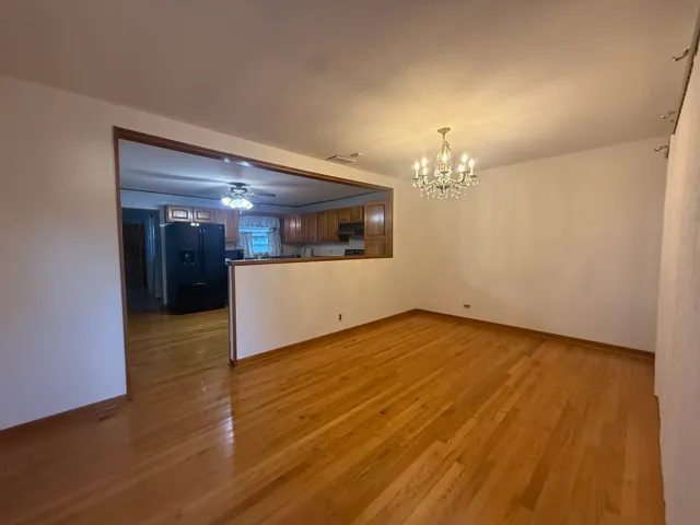 a view of a hallway with wooden floor and a kitchen