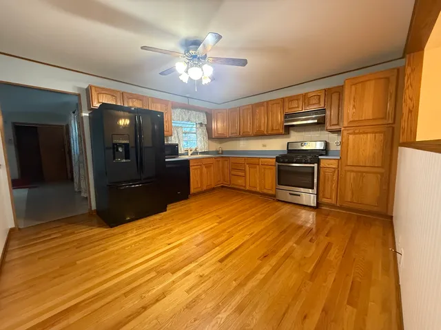 a kitchen with stainless steel appliances wooden floor sink and refrigerator