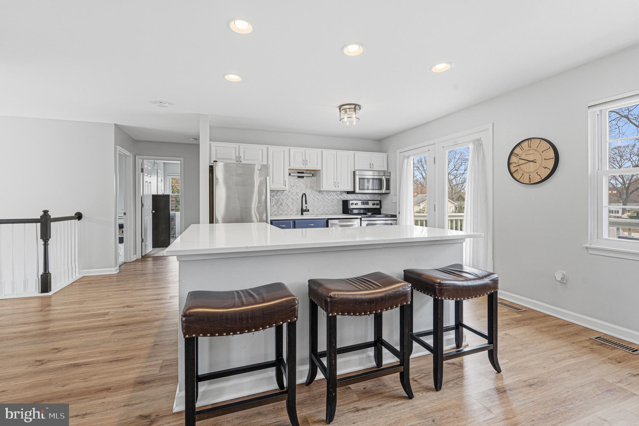243 9th Street Pasadena, MD 21122 - Photo 10 of 41 a kitchen with kitchen island a dining table chairs cabinets and a sink