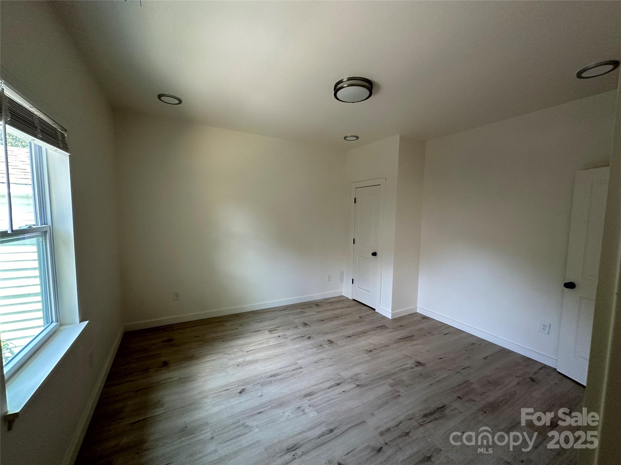 1409 Enochville Road Kannapolis, NC 28081 - Photo 8 of 14 an empty room with wooden floor and windows