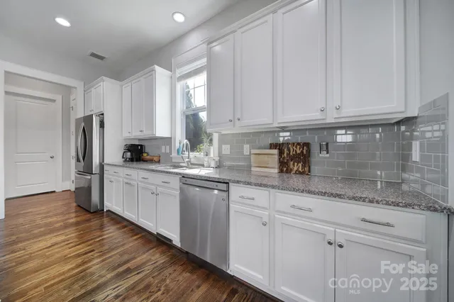 a kitchen with stainless steel appliances granite countertop a refrigerator sink and white cabinets