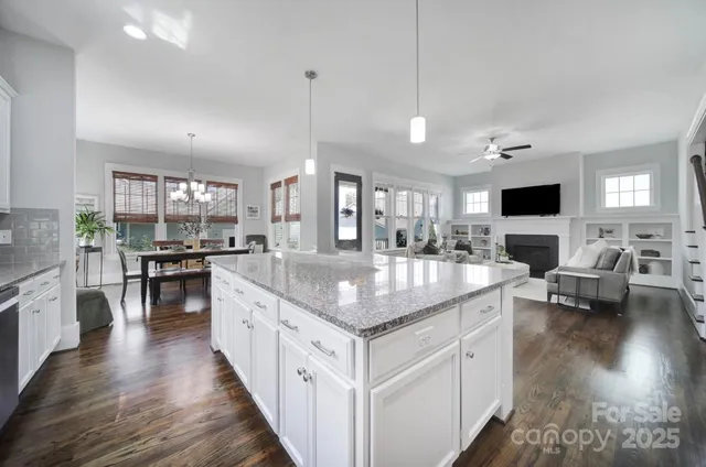 a kitchen with stainless steel appliances granite countertop a stove top oven a sink a dining table and chairs with wooden floor