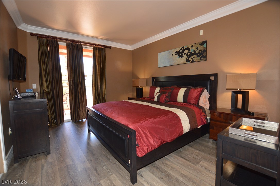 220 East Flamingo Road, Unit 327 Las Vegas, NV 89169 - Photo 5 of 13 Elegant crown molding adorns this spacious bedroom, featuring durable hardwood flooring.