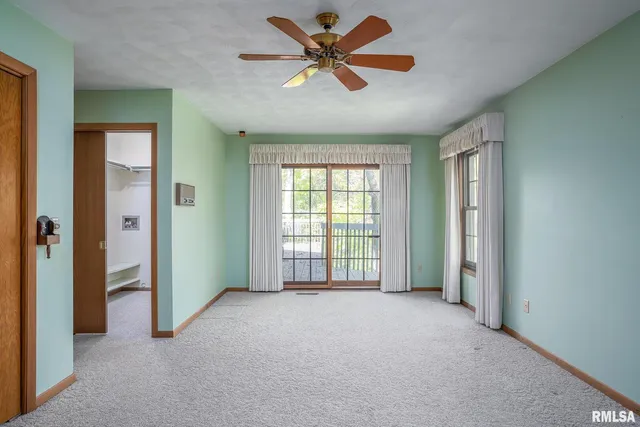 an empty room with chandelier fan and windows