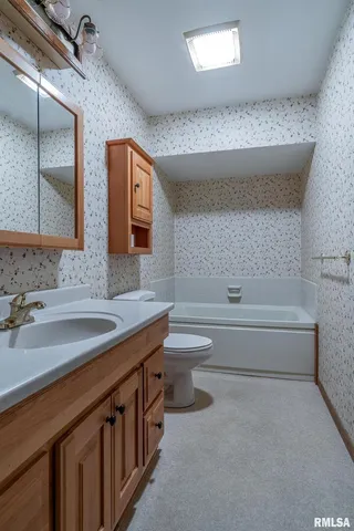 a bathroom with a double vanity sink a toilet and bathtub