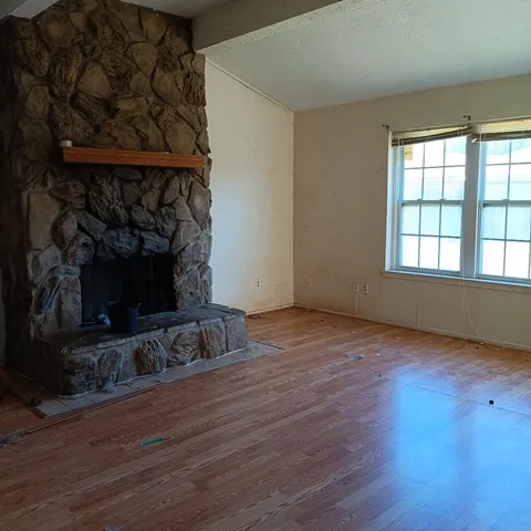 an empty room with wooden floor and a fireplace