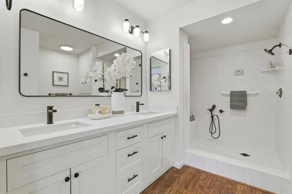 a bathroom with a shower sink double vanity and mirror