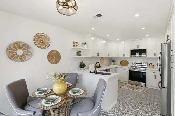 a kitchen with a dining table cabinets and stainless steel appliances