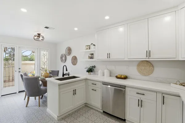 a kitchen with a sink dishwasher and white cabinets with wooden floor
