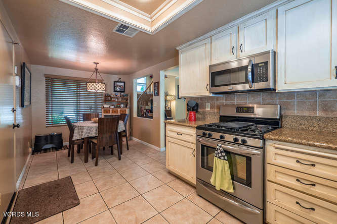 40 Valley Crest Road Simi Valley, CA 93065 - Photo 18 of 38 a kitchen with stainless steel appliances granite countertop a stove top oven a sink dishwasher a dining table and chairs with wooden floor