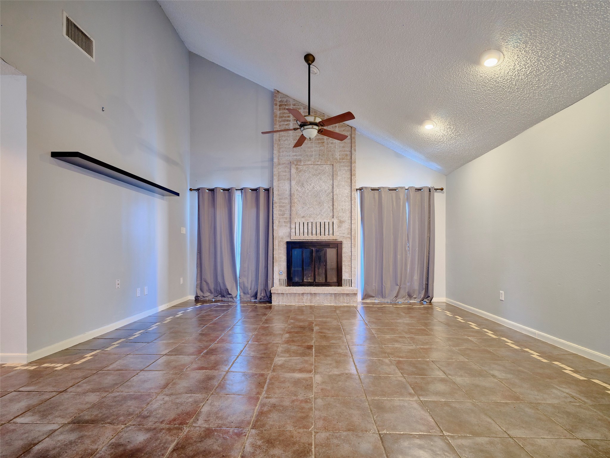 a view of an empty room with a fireplace and a window