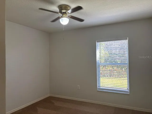 an empty room with a window and a ceiling fan