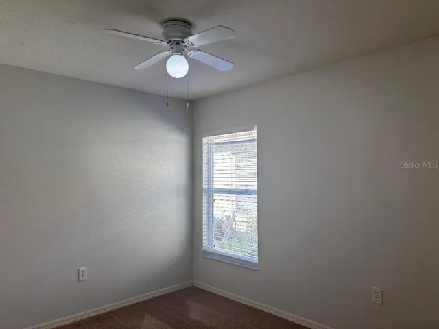 an empty room with windows and fan