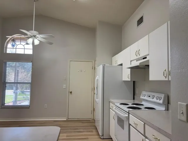 a kitchen with cabinets appliances and wooden floor
