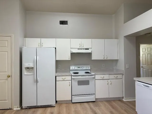 a kitchen with granite countertop a sink a stove and refrigerator