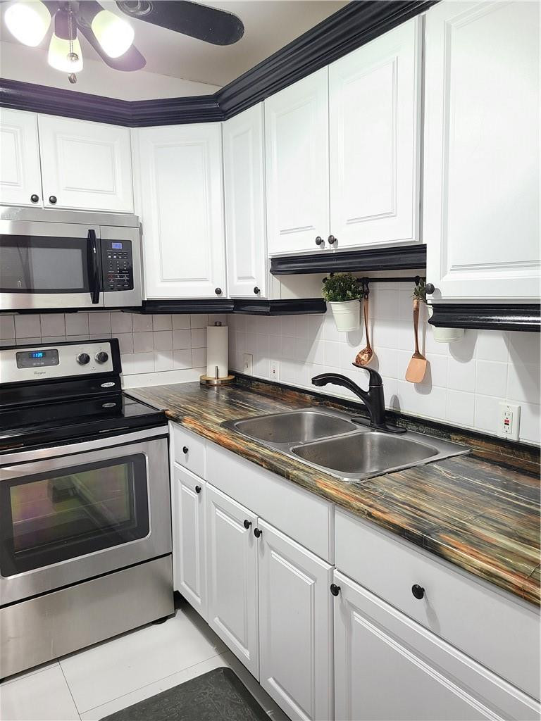 163 Suffolk F, Unit 163 Boca Raton, FL 33434 - Photo 13 of 34 a kitchen with stainless steel appliances granite countertop a sink a stove and a microwave