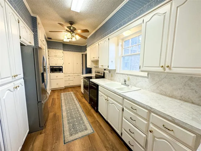 a large kitchen with granite countertop a large window appliances and cabinets