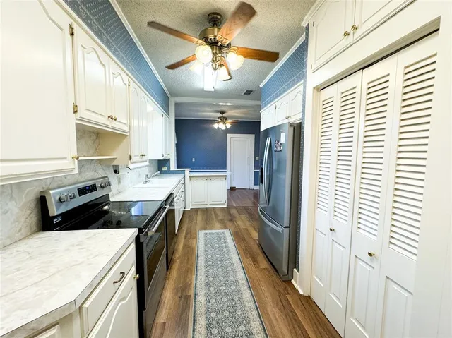 a kitchen with stainless steel appliances granite countertop a refrigerator a sink dishwasher a stove and white countertops with wooden floor