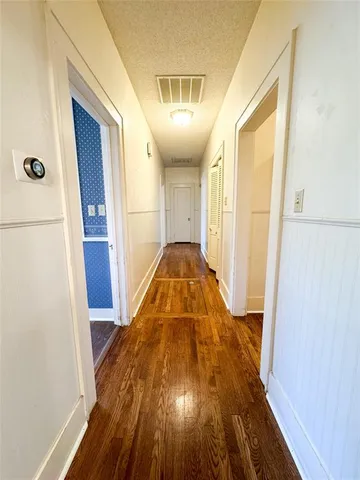 a view of a hallway with wooden floor and cabinet