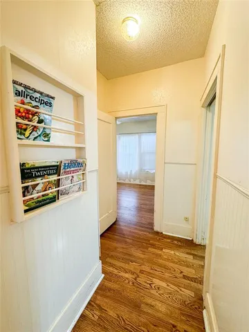 a view of a hallway to an empty room and wooden floor