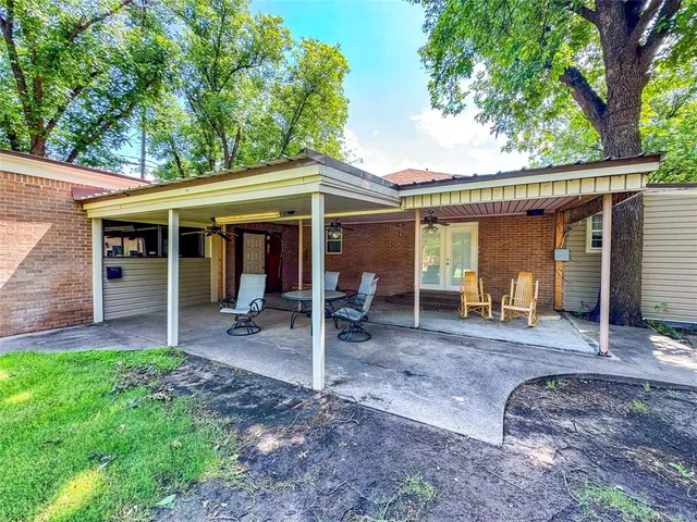 a view of a house with a yard patio and a large tree