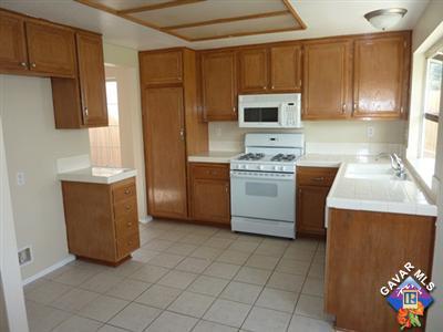 1539 Kings Road Palmdale, CA 93551 - Photo 7 of 22 a kitchen with stainless steel appliances a stove a microwave a sink a refrigerator white cabinets and wooden cabinets