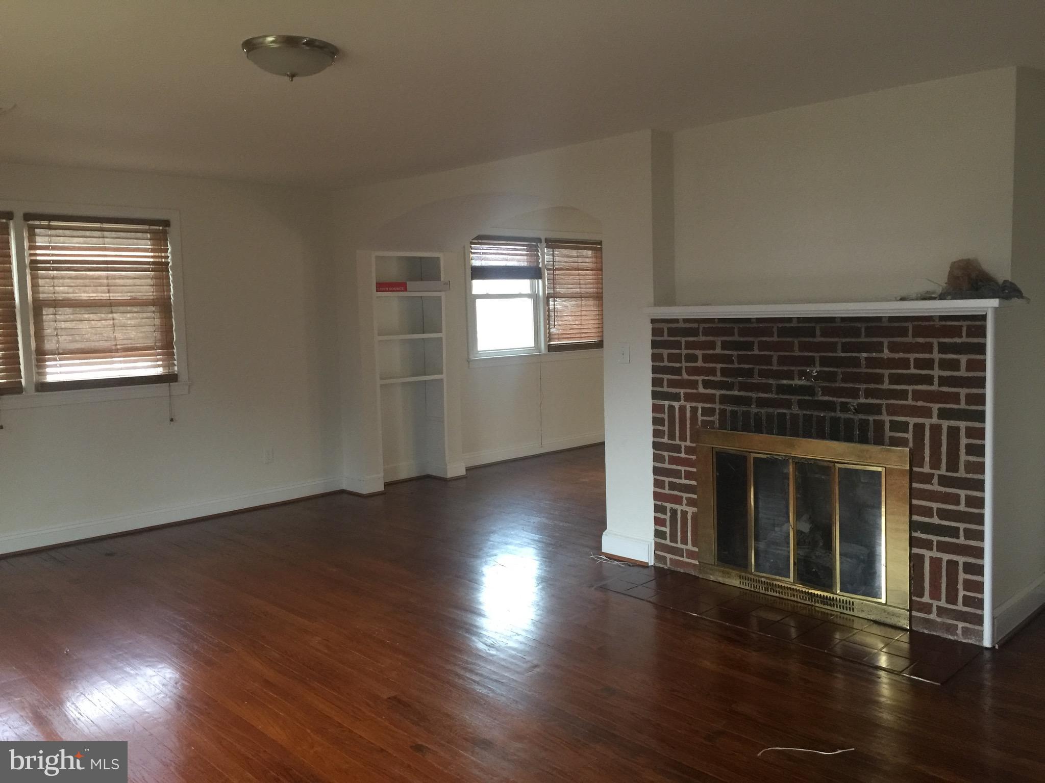 9101 Sudley Road Manassas, VA 20110 - Photo 10 of 16 an empty room with wooden floor fireplace and windows