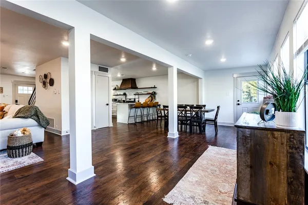 a kitchen with stainless steel appliances granite countertop a refrigerator a sink dishwasher a stove and white cabinets with wooden floor