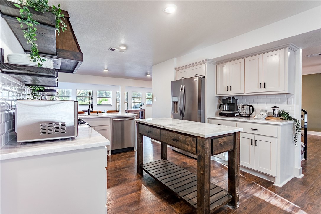 107 Spring Creek Street Waco, TX 76705 - Photo 24 of 78 a kitchen with stainless steel appliances granite countertop a stove a refrigerator a sink dishwasher and a stove with wooden floor