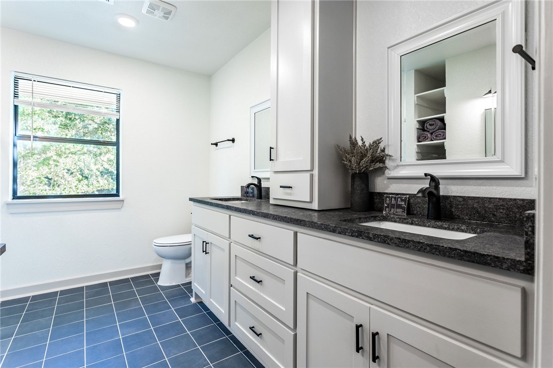 107 Spring Creek Street Waco, TX 76705 - Photo 48 of 78 a bathroom with a granite countertop sink a toilet and mirror