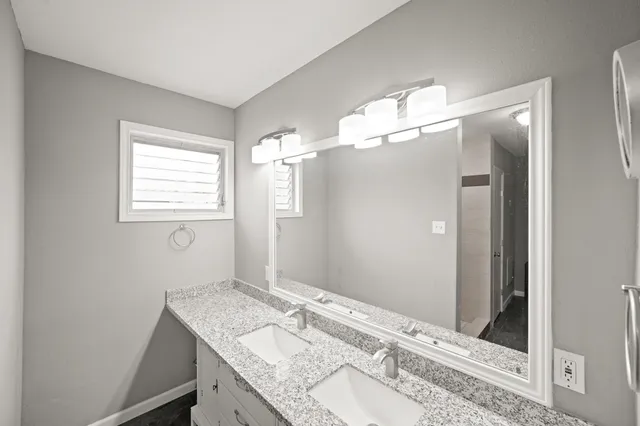a bathroom with a granite countertop sink a mirror and a shower