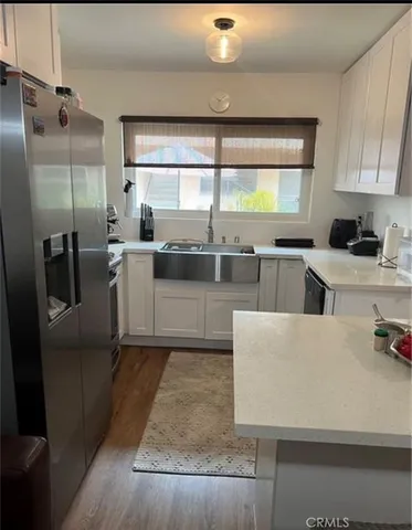 a large kitchen with stainless steel appliances a sink a stove a refrigerator a counter top space and cabinets